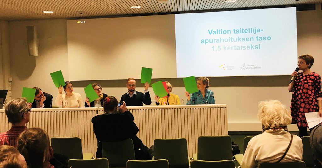 Tampereen pääkirjasto Metso 26.3.2019. Panelistit Jukka Gustafsson (SDP), Anna Kontula (Vas.), Pilvi Kärkelä (Kesk.), Olli-Poika Parviainen (Vihr.) ja Sofia Vikman (Kok.) nostavat vihreän lapun ilmaan valtion taiteilija-apurahoituksen tason nostamisen puolesta. Jaana Ristimäki-Anttila (PS) empii.